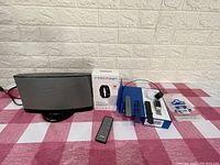 Bose speaker system with remote, Fitbit Charge 2 box, watch, and three extra bands displayed on a checkered cloth.