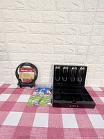 Full lot contents showing Blackburn bike lock in stand, Master Lock cash box, and accessories on checkered surface with background wall.