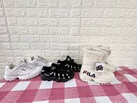 Three pairs of shoes from left to right: white athletic shoes, black athletic shoes, white winter boots with fur and tags