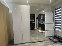 Exterior view of two assembled PAX wardrobe frames side by side, one with white doors and one with mirrored doors