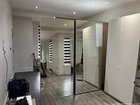 Two IKEA PAX sliding wardrobe doors standing side by side showing the mirror fronts reflecting a bright room.