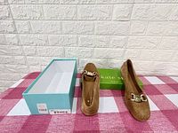 Tan suede Kate Spade flats with metal chain detail alongside their green Kate Spade box, brand new condition.