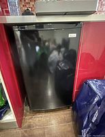 Front view of the black Magic Chef mini refrigerator fitted under a counter.