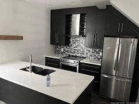 Wide view of the white quartz countertop installed in kitchen with black double undermount sink and faucet.