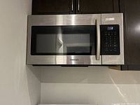 Microwave installed under cabinetry showing front view with control panel and handle