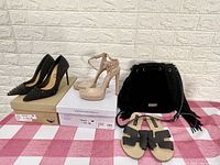 Photo showing three pairs of women's shoes and one black suede purse on a pink checkered cloth with a white brick background.