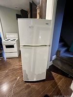 Front view of white Whirlpool refrigerator, showing overall condition and size relative to kitchen appliances.