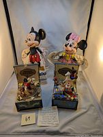 Photo showing two hand puppets and two vintage music boxes side by side on cloth background.