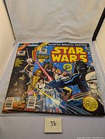 Photo showing two vintage Star Wars Marvel Special Edition comics with colorful covers and a small sticky note marked '56'