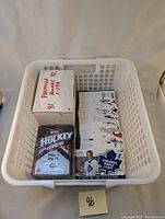 Top view of a white basket containing a sealed 1990-91 Upper Deck NHL Hockey High Series 2 box, Premier Hockey 91-92 box, and a stack of loose hockey cards including a visible Toronto Maple Leafs logo card.