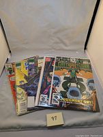 Nine vintage comic books including DC Comics Green Lantern and New Teen Titans, displayed in protective sleeves with clear cover art.
