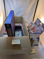Wide shot of cardboard box with baseball card binders, countless cards, and boxed mini-figures of Jim Edmonds and Tommy Lasorda.