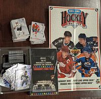 Stacks of assorted hockey cards, sealed OHL Tomorrow's Stars box, and NHL hockey poster on wooden surface