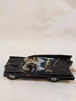 Side view of the black diecast Batmobile with Batman and Robin figures inside.
