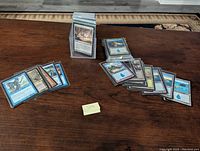 Photo showing stacks of sleeved vintage Magic the Gathering cards, including blue lands and other cards.