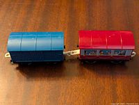 Photo of the blue and red train cars connected, showing the top and side of each car.