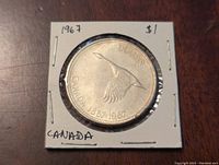 Obverse side of 1967 Canadian silver dollar coin showing flying goose and inscriptions.
