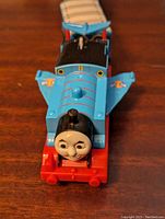 Front view of blue Thomas the Tank Engine with attached blue wings, smiling face visible.