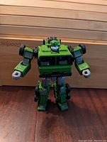 Transformers Generations Legacy Bulkhead figure in robot mode standing upright on wooden surface.