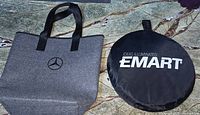 Image showing both the Mercedes-Benz tote bag and EMART light controller carrying case side by side on a stone surface.
