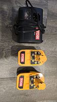 Top view showing Ryobi branded black battery charger and two yellow 18V batteries