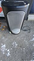 Full front view of the black Fellowes paper shredder with large metal mesh basket and power cord on ground.