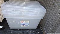 Stack of three clear plastic IRIS storage bins with lids, showing the overall condition and size.