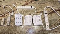 Top view of various extension cords and power strips laid out on a surface showing multiple electrical outlets and inline switches.