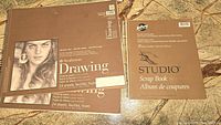 Two Strathmore Drawing notebooks and one Hilroy Studio Scrap Book on a tiled floor.