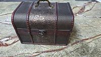 Front view of wooden treasure chest with embossed floral design and clasp