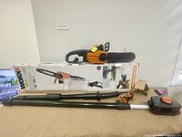 Worx brand chain saw and pole saw attachment laid out with original box in background.