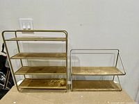 Front view of two wooden wall shelves with gold metal framing, one tall with 4 shelves and one smaller with 2 shelves