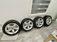 All four tire-rim assemblies leaning against wall
