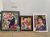 Overview photo showing all three art prints framed and placed side by side on a carpeted floor against a wall with a water bottle for scale.