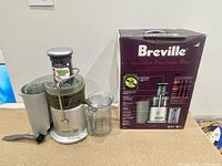 Breville Juice Fountain Plus juicer unit with pulp container, juice jug and original box visible in background.