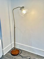 Full view of glass globe floor lamp lit in corner against white wall