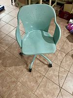 Front view of teal metal desk chair showing perforated seat and backrest, curved armrests, and caster wheels.
