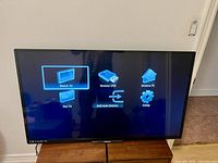 Front view of Philips TV screen displaying menu interface showing Watch TV, Browse USB, Browse PC, Net TV, Add new devices, and Setup options.