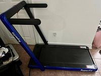 Side view of blue SuperFit treadmill showing foldable handrails and running belt