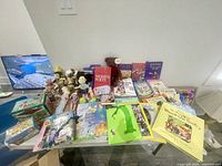 Wide shot of vintage children's books, dolls, plush toys, and game boxes arranged on a table.