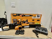 Overview showing chainsaw, two batteries, dual charger and original box.
