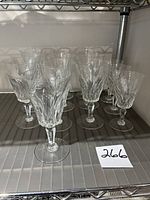 Group of 13 Baccarat crystal wine glasses on shelf showing both sizes.