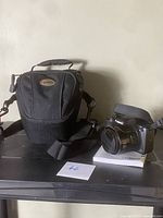 Canon Powershot SX530 HS camera with carrying bag and manual placed on surface