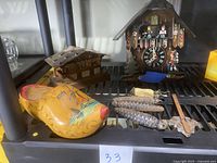 Photo showing wooden yellow Dutch clog with colorful hand-painted outdoor scene, Swiss chalet music box, and cuckoo clock parts including pine cone pendulum weights and decorative figurines.