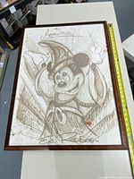 Full framed artwork showing 'The Apprentice' Mickey Mouse sketch with framing and measurement tape for size reference.