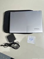 Top view of Lenovo Yoga 730 laptop closed on top of black soft case with power adapter beside it.