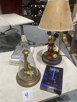 Photo showing Fantasia clock under glass dome with Mickey Mouse lamp and Fantasia DVD box nearby.