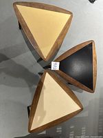 Top view of three triangle tables showing cream and black tops with wood frames.