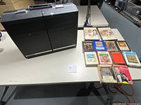 Black Panasonic RF-7180 8 track/am/fm radio player with connected power cord and carrying handle, sitting beside 12 8 track tapes.