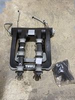 Top-down photo of Thule 3-bike trunk rack with padded bike support arms and straps, showing overall condition and included keys in plastic bag.